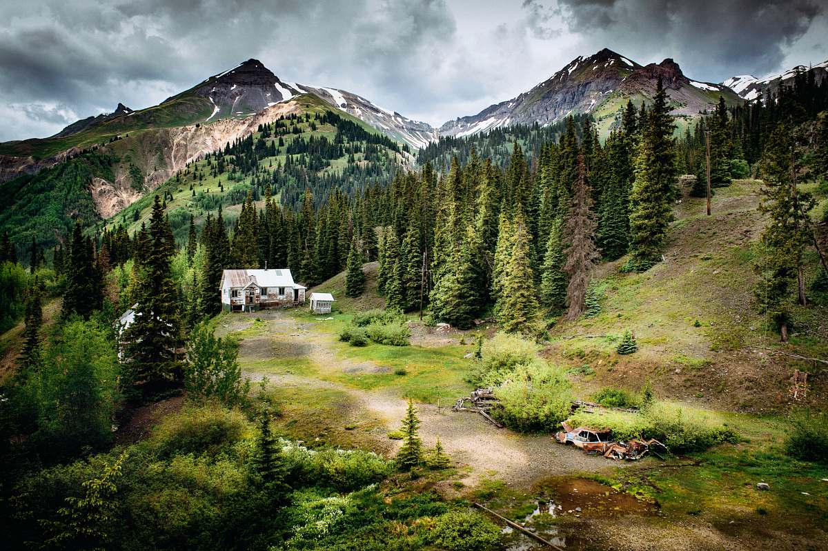 red mountain white house surrounded with pine trees near mountain mountain